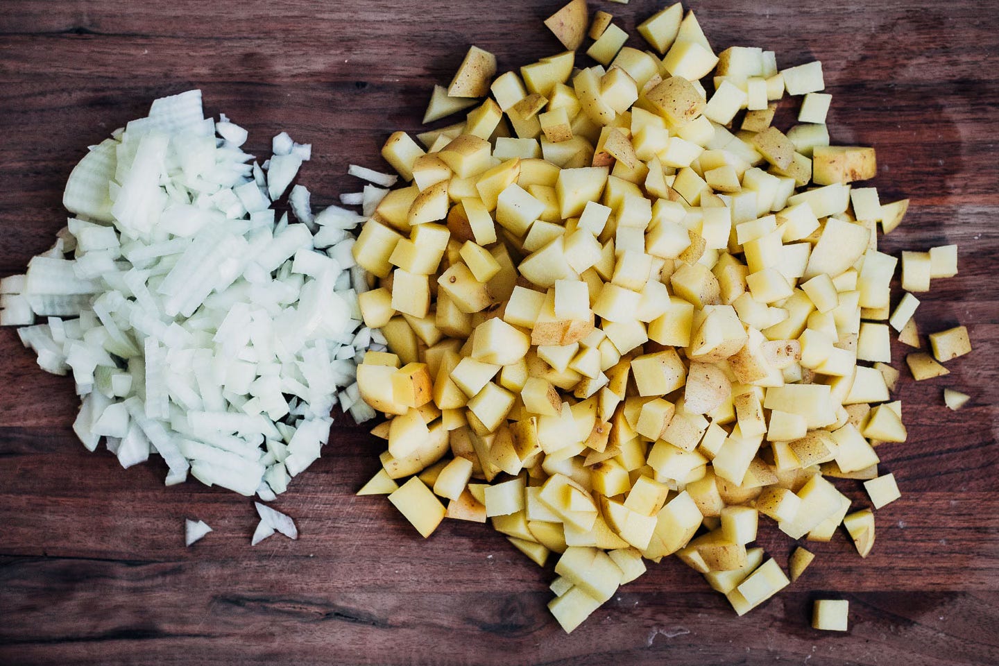 Chopped onions and potatoes on a cutting board. 