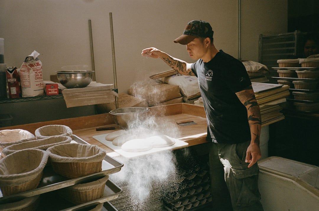 Alessandro Jang tosses flour onto loaves before shaping