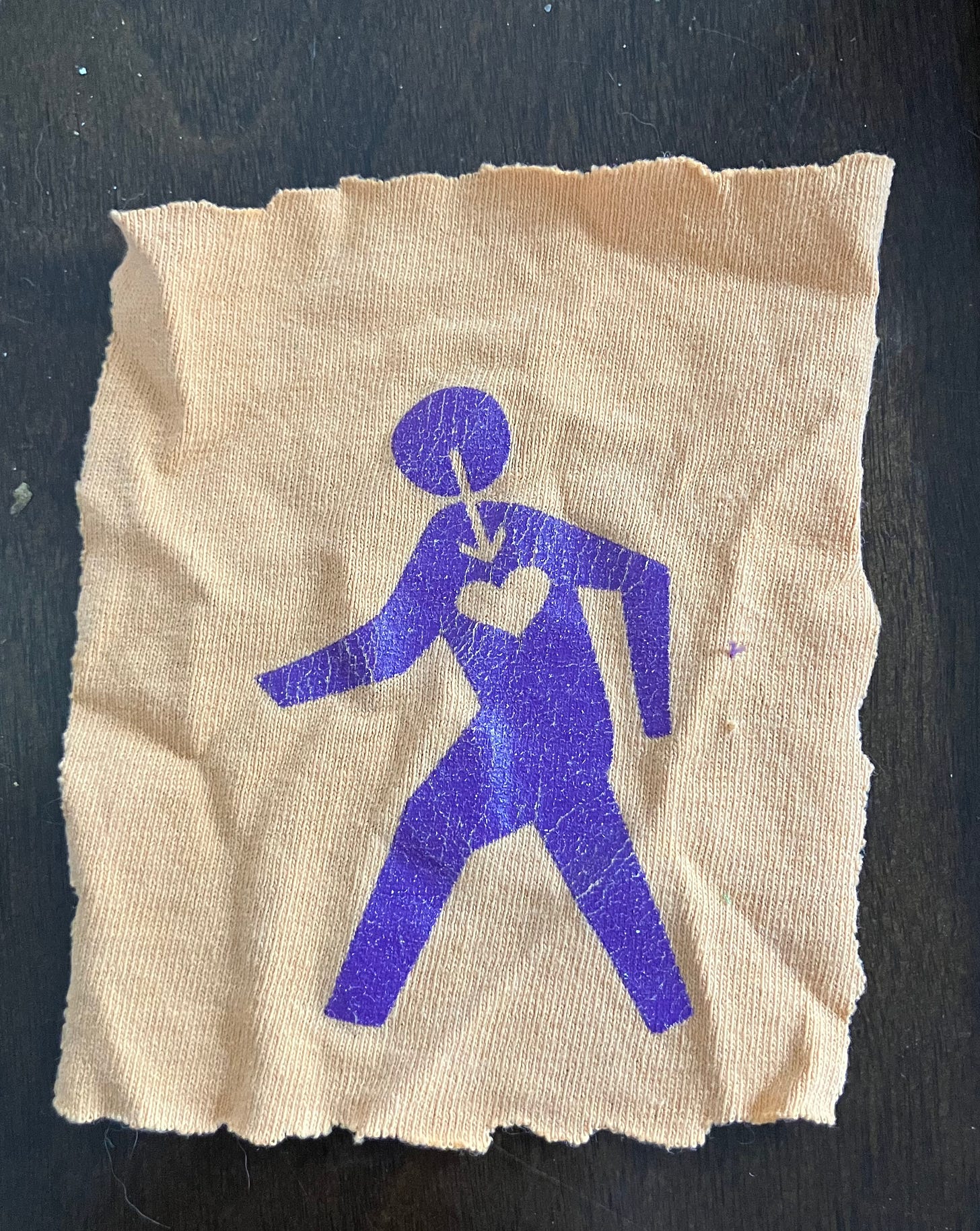 An orange piece of fabric with a purple human figure depicted on it. There is an arrow inset pointing down from the head to a heart shape on the figure's chest. An orange piece of fabric with a purple human figure depicted on it. There is an arrow inset pointing down from the head to a heart shape on the figure's chest.