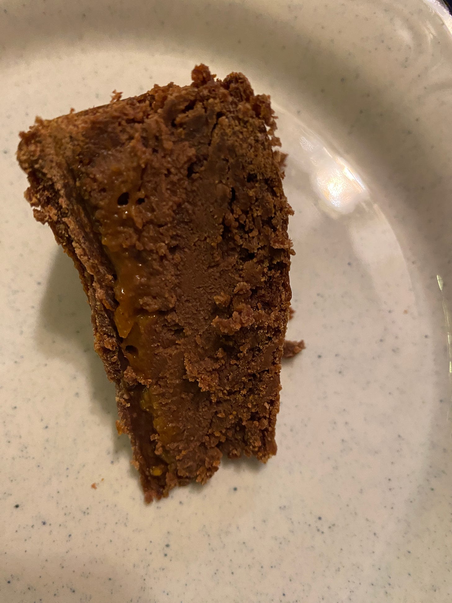 A slice of chocolate cake, called Chocolate Candied Orange Gâteau, on a white flecked plate.