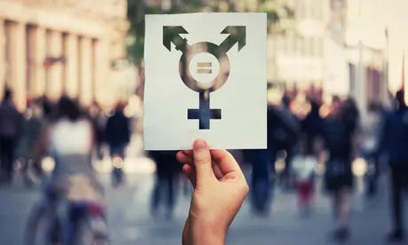 Hand holding a paper sheet with transgender symbol and equal sign inside. Equality between genders concept over a crowded city street background. Sex<br>RFH366 Hand holding a paper sheet with transgender symbol and equal sign inside. Equality between genders concept over a crowded city street background. Sex