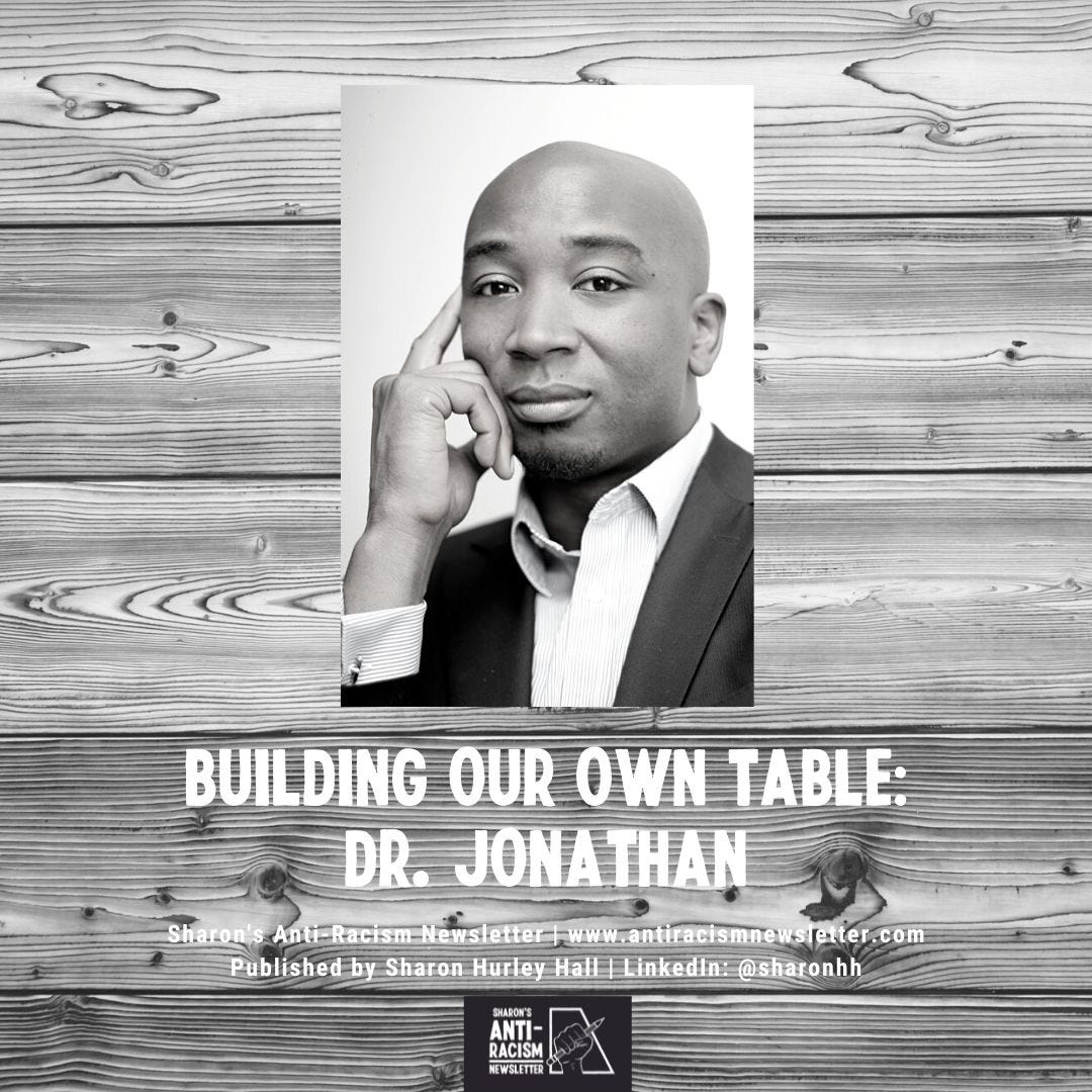 Building Our Own Table: Dr Jonathan. Published on Sharon's Anti-Racism Newsletter. Photo of Dr Jonathan Ashong-Lamptey in a dark suit and light shirt set against a wooden background