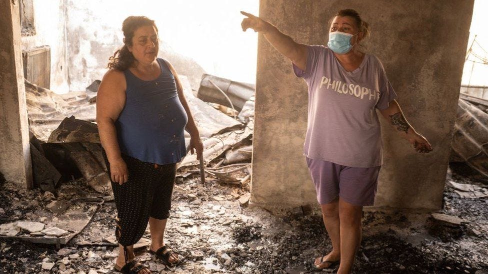 residents check the rooms of a destroyed house after wildfires engulfed the area of Acharnes