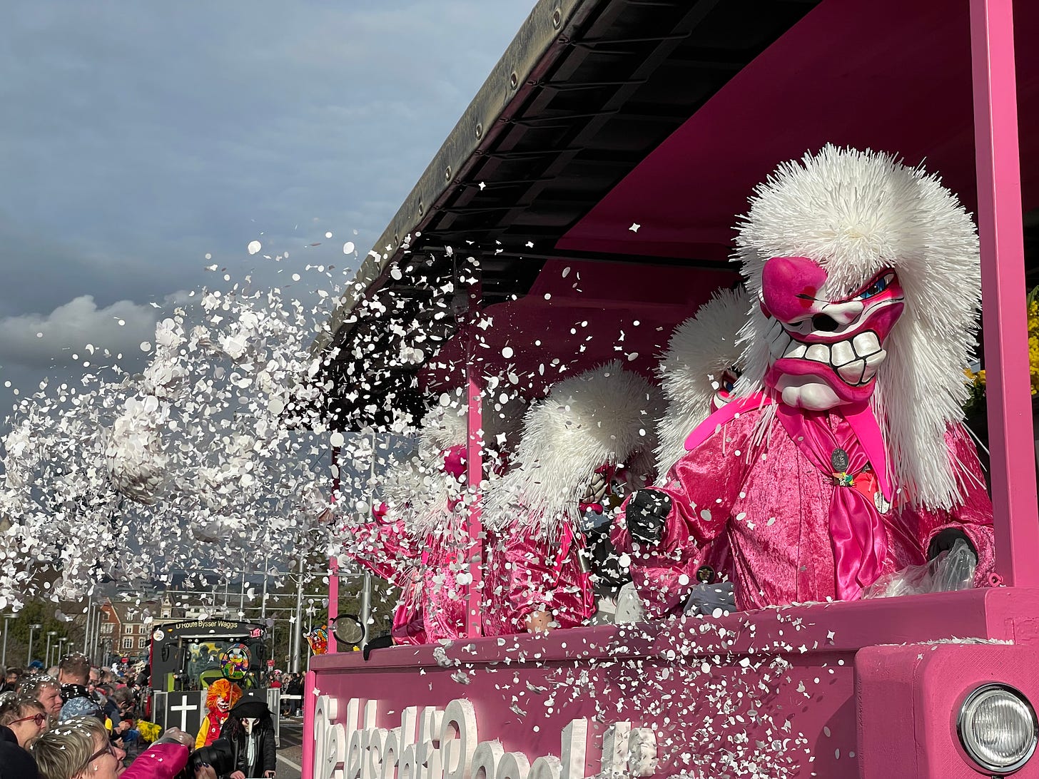 A pink and white Waggis throws confetti at Basel's Fasnacht.