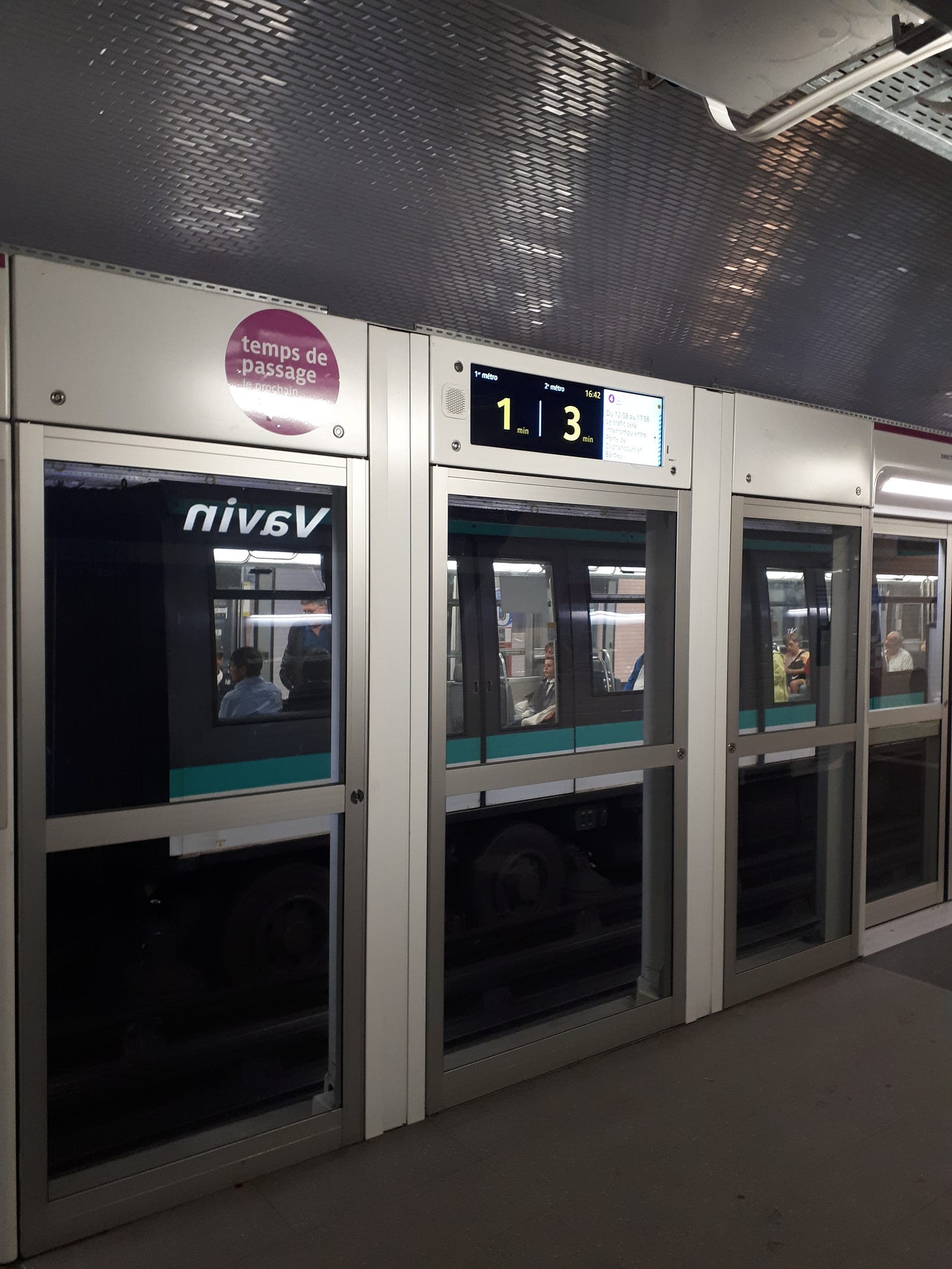 Subway station with a sign above noting the next trains are arriving in 1 and 3 minutes.