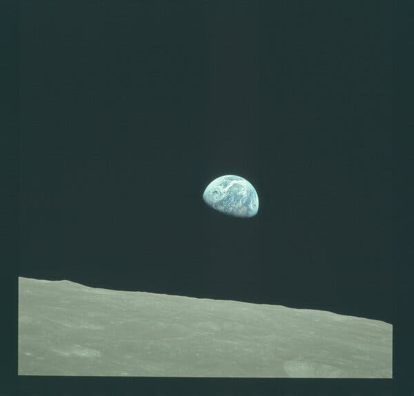 An image of the half-illuminated earth with a gray lunar landscape in the foreground.