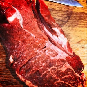 A slice of Chuck steak on a chopping board with great inter muscular marbling.