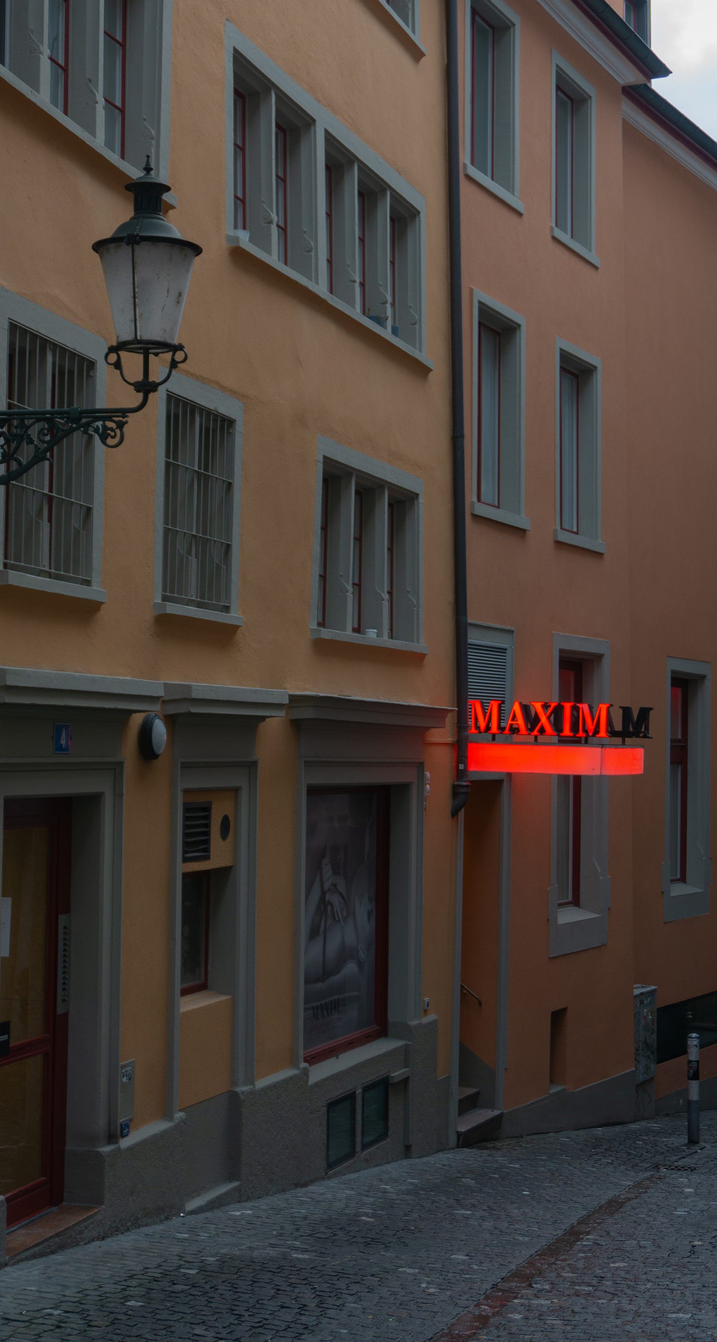 A photo of clean buildings, one has read neon sign and a photo of scantily clad woman