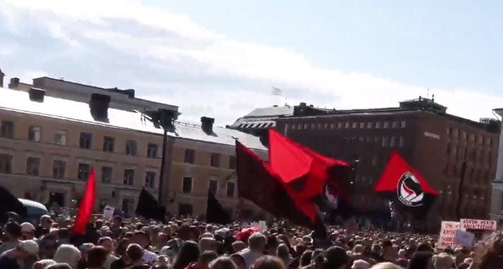 Punaiset sirppi ja vasara-, sekä anarkistiliput näkyivät selkeästi mielenosoittajien joukoista. (Kuva: Kuvankaappaus videosta.)
