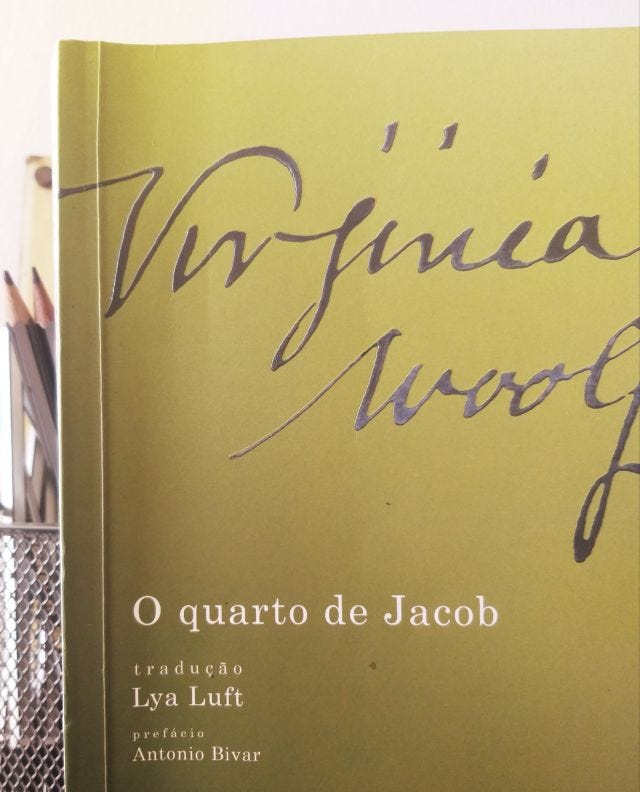 descrição: foto do meu acervo pessoal dacapa do livro "O quarto de Jacob" de Virginia Woolf e ao fundo, à esquerda, alguns lápis com a ponta para cima em um pote de metal.