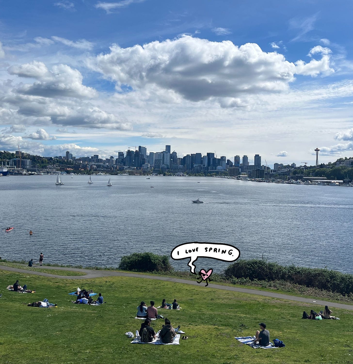 A photo of Gas Works Park in Seattle on a sunny day, with a little heart character drawn on top. A speech bubble reads, "I love spring."