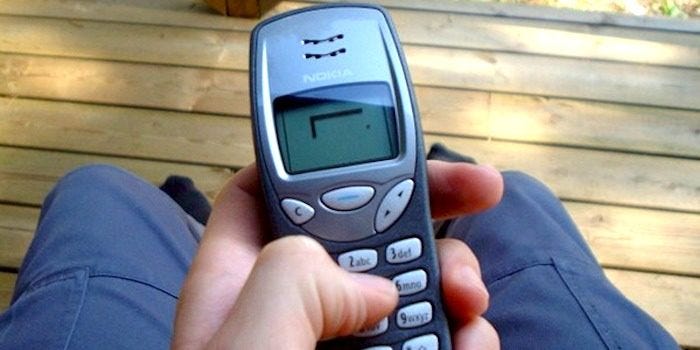 A person holding a Nokia phone and playing the game Snake