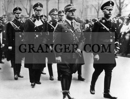 HIMMLER AND ROHM, 1934. 
German soldier and National Socialist leader Ernst Röhm (center) and Gestapo chief and Reichsführer-SS Heinrich Himmler (right) at a memorial service for SS lieutenant commander Siegfried Seidel-Dittmarsch in Berlin, 1934.