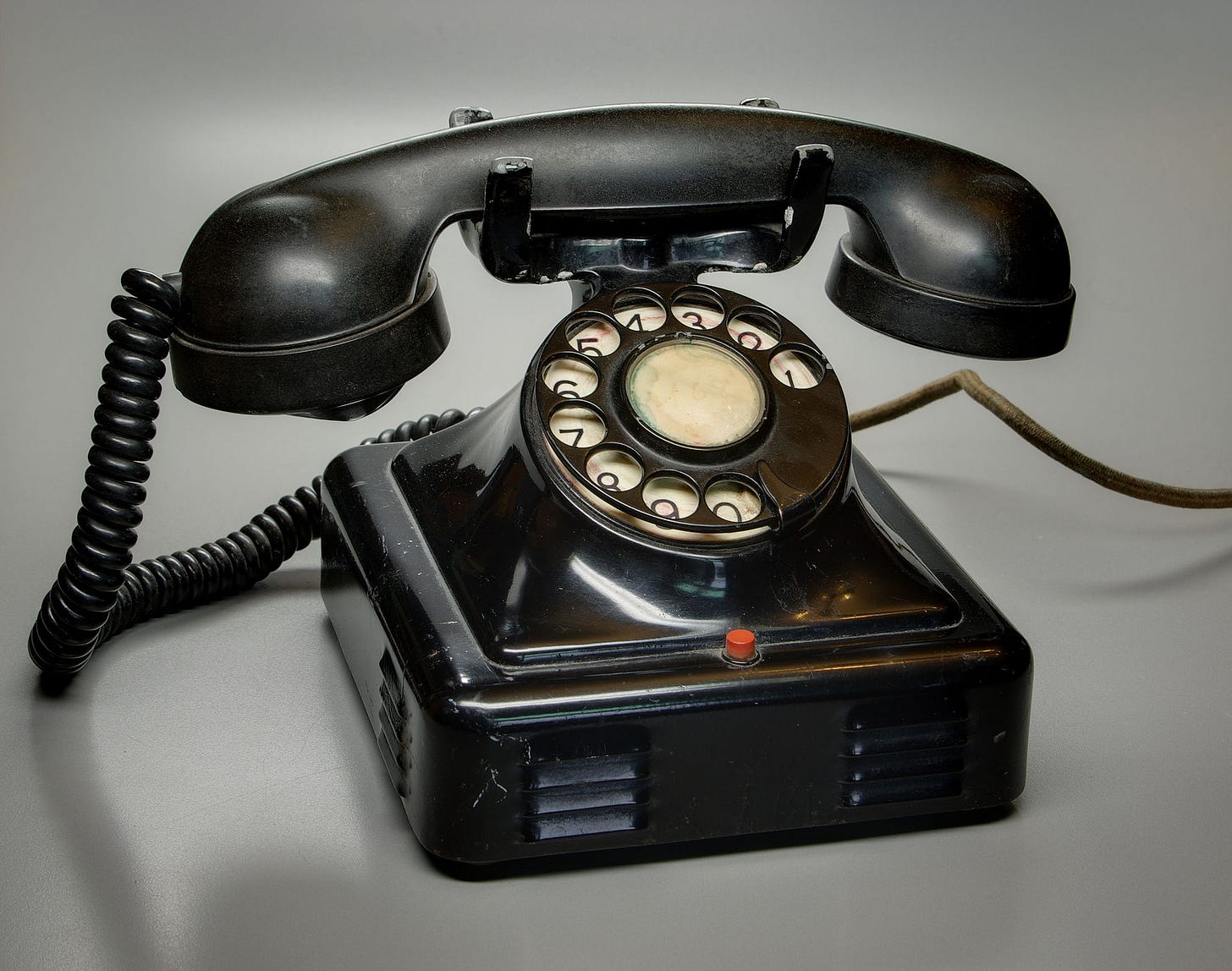 A black rotary phone on a grey background, poached from Wikipedia.