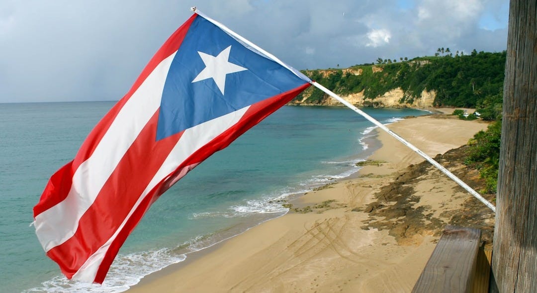 red and white flag on beach shore during daytime red and white flag on beach shore during daytime
