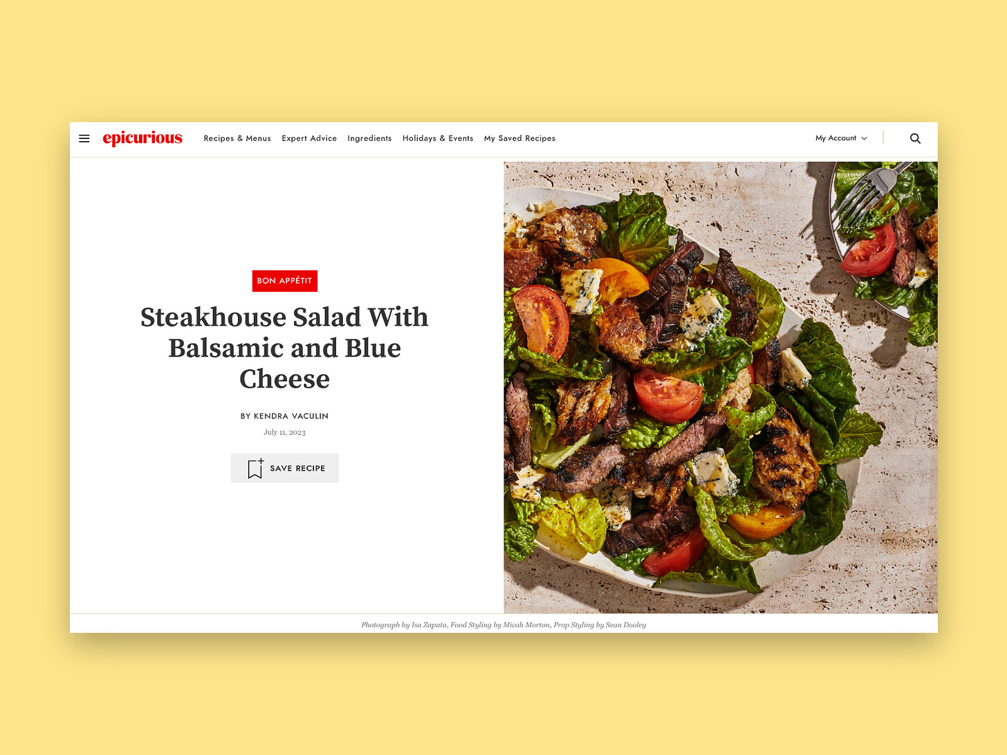 A screenshot of the food recipe website Epicurious, set against a yellow background. The screenshot shows the red Epicurious logo in the upper left-hand corner. Below is a recipe, with the title “steakhouse salad with balsamic and blue cheese” on the left side of the page. Directly above the name of the recipe is a red label that says “Bon Appetit.” To the right is a photo of a salad, with lettuce, sliced tomatoes, and grilled chicken on a white plate. 