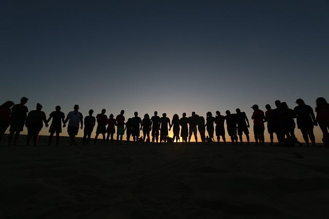 Group of people in shadow in front of sunrise