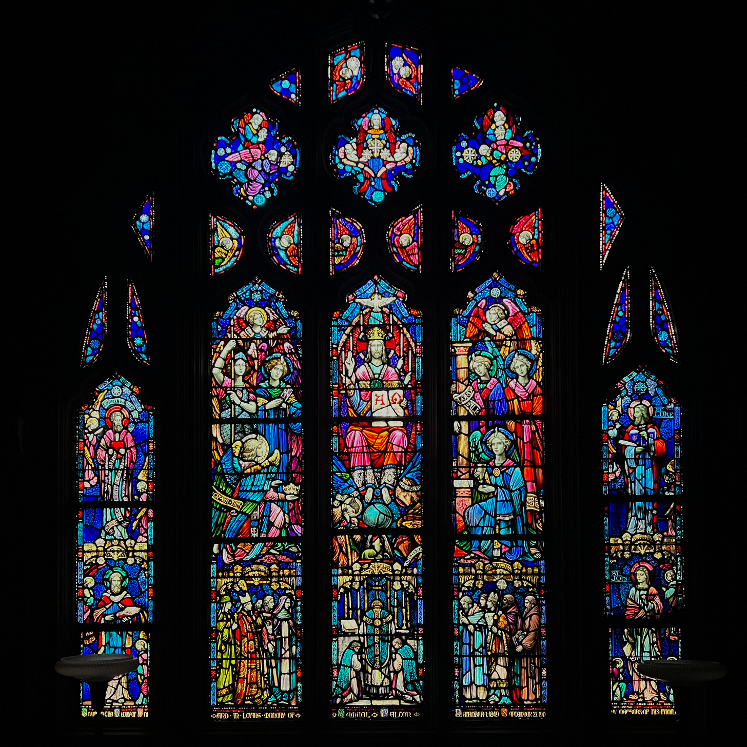 A five-lancet stained glass window featuring Christ enthroned as King and surrounded by angels, saints, and the faithful.