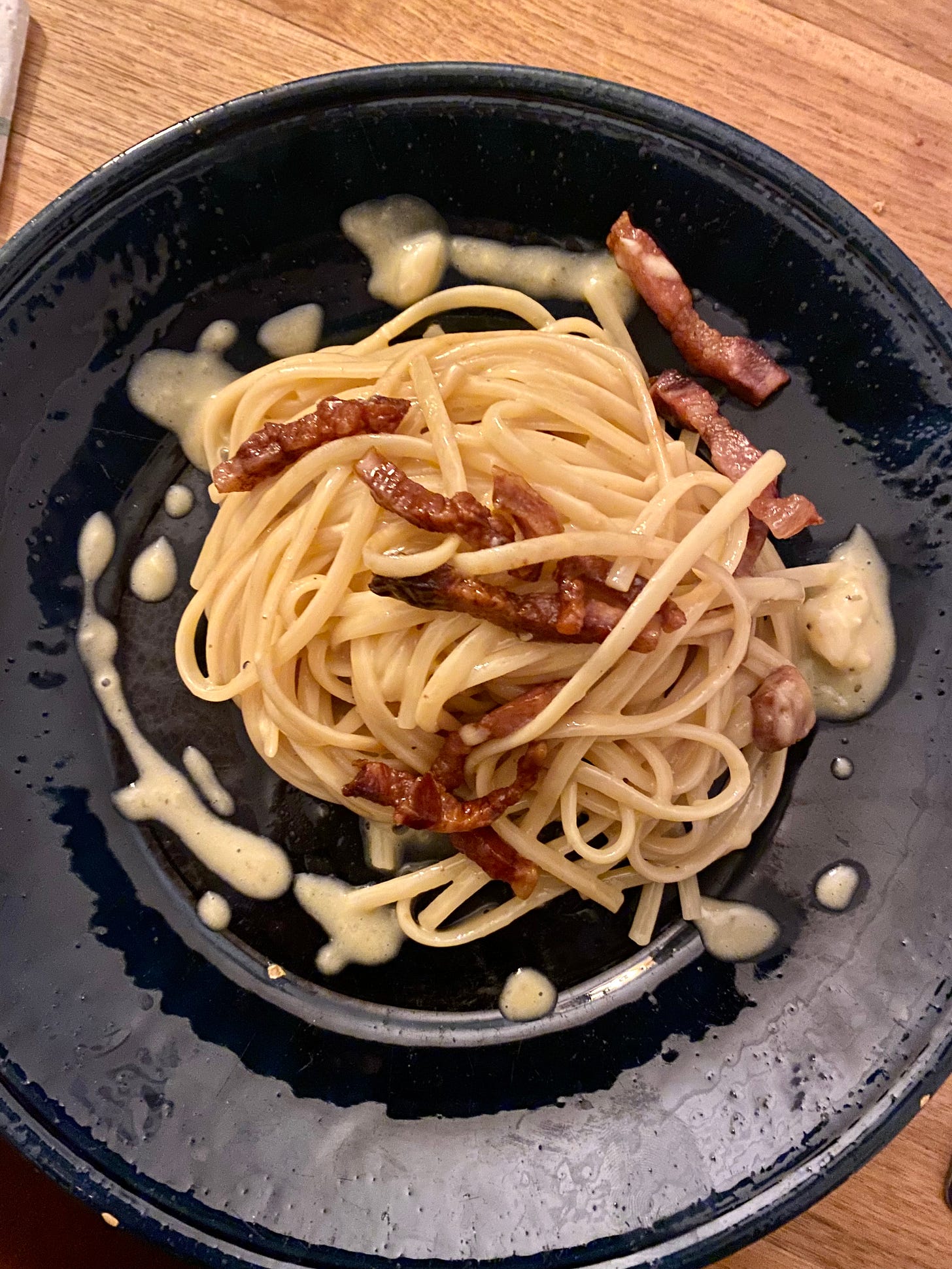 Carbonara on a blue plate with sauce surrounded