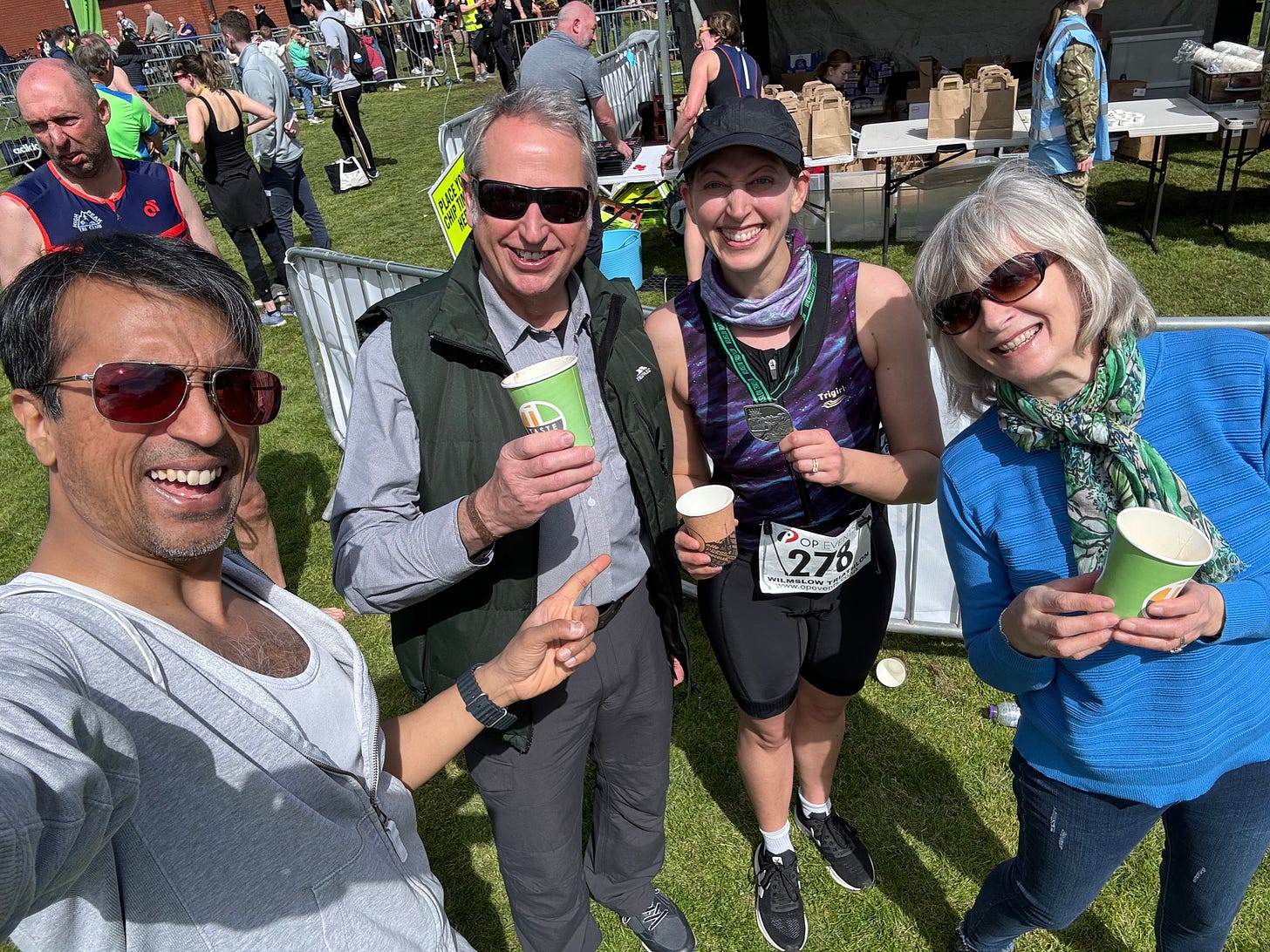 Photo of me with my triathlon medal with my parents and Vikas at the finish line