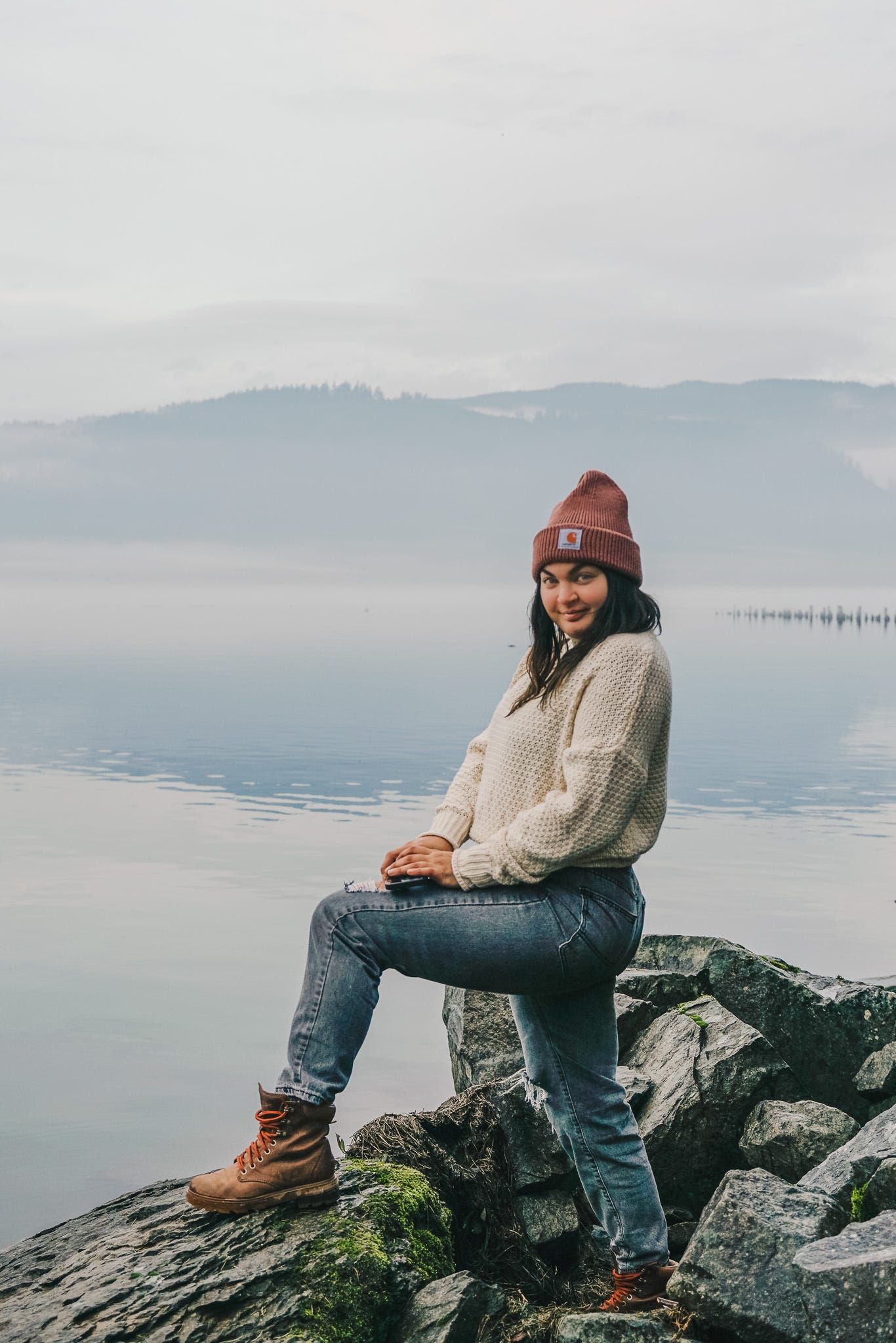 The author, Caitie, posing on a rocky shore with a slight smirk on her face that she has a secret she wants to share