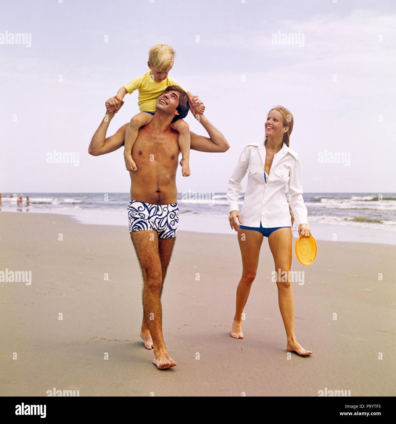 1970s YOUNG FAMILY WALKING DOWN BEACH TODDLER RIDING ON FATHERS SHOULDERS -  kb11593 HAR001 HARS CLOTHING SHOULDERS NOSTALGIC PAIR COLOR MOTHERS OLD  TIME NOSTALGIA OLD FASHION 1 JUVENILE STYLE SONS FAMILIES JOY