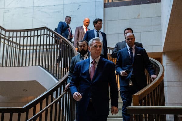 Kevin McCarthy walking down a spiral staircase in the Capitol followed by other men wearing suits.