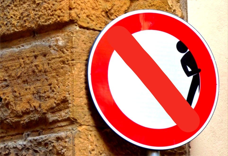 man hiding signage on brick wall
