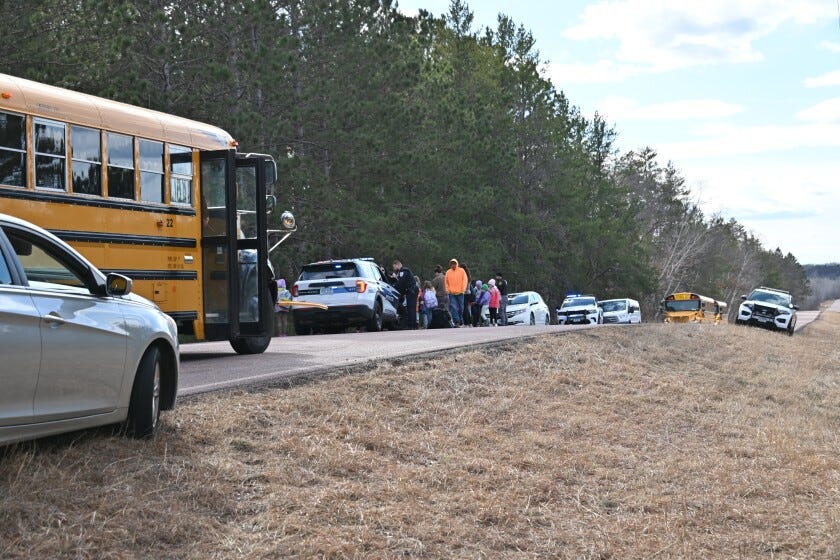 Kids on the side of the road with buses and emergency response vehicles.