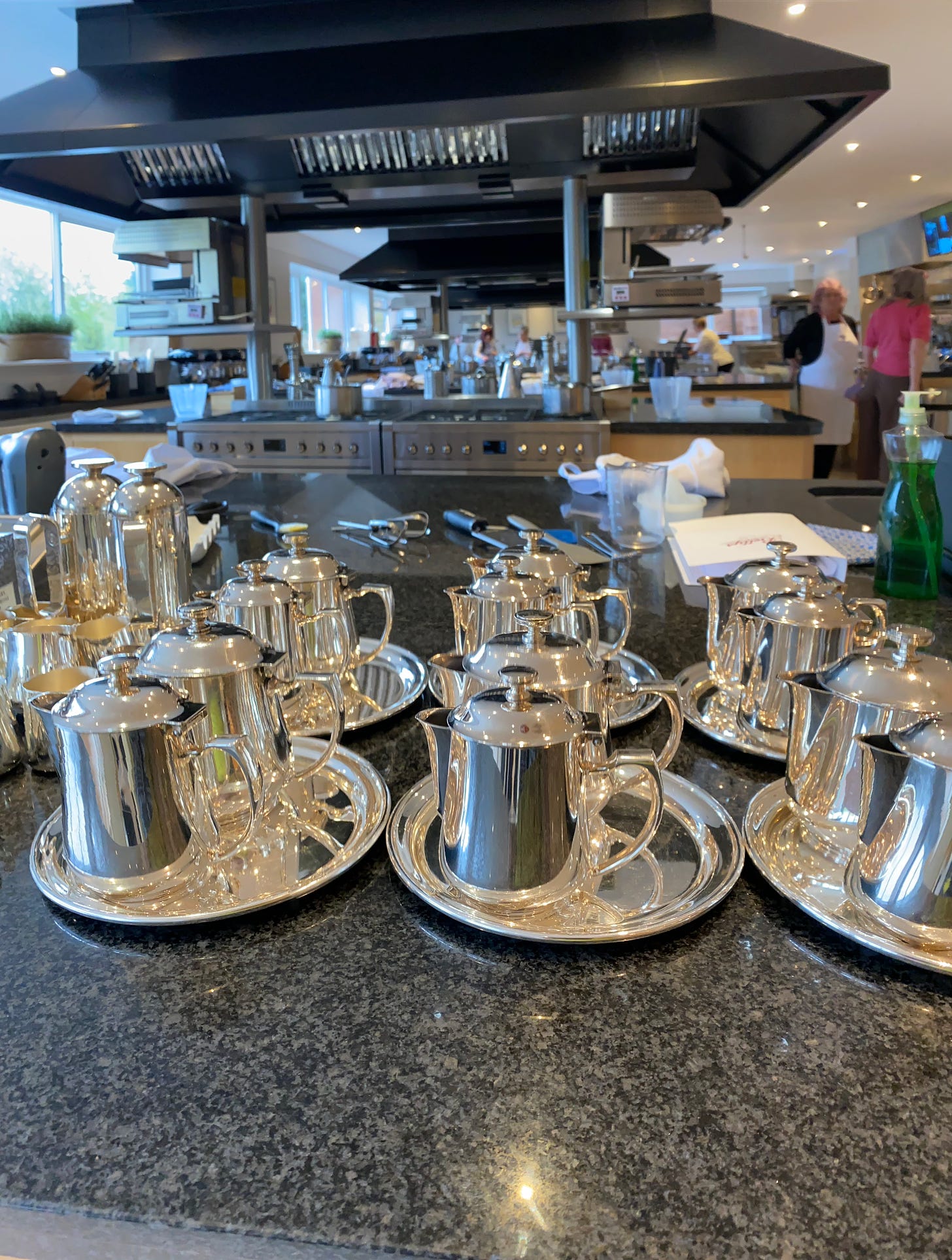 Bettys Cookery School kitchen, with rows of silver tea pots in the foreground.