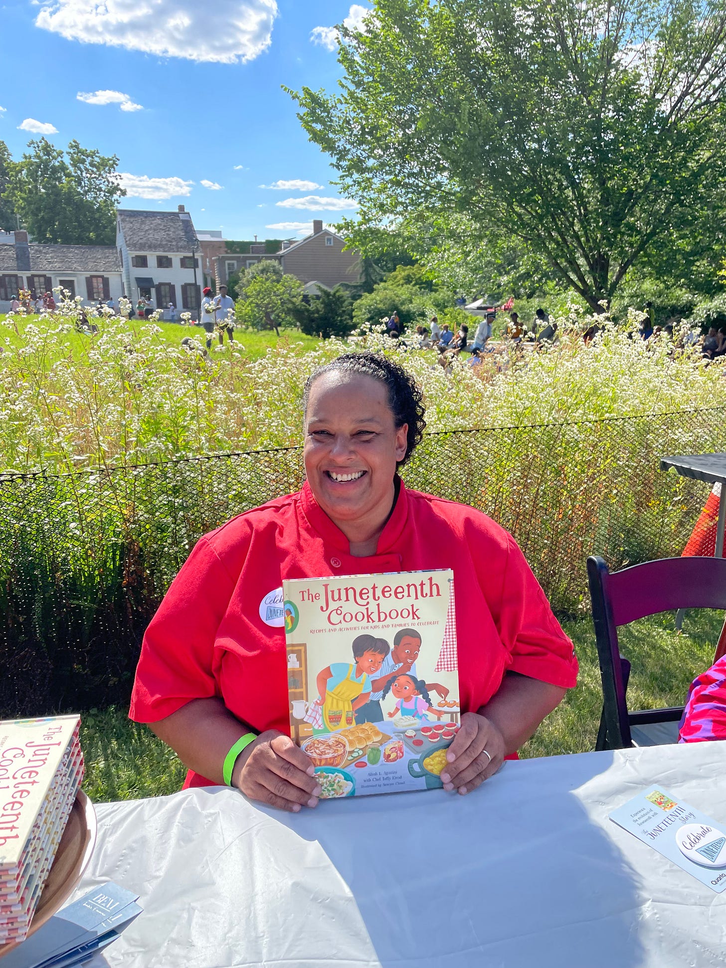 Taffy holding up The Juneteenth Cookbook sitting at a table outside