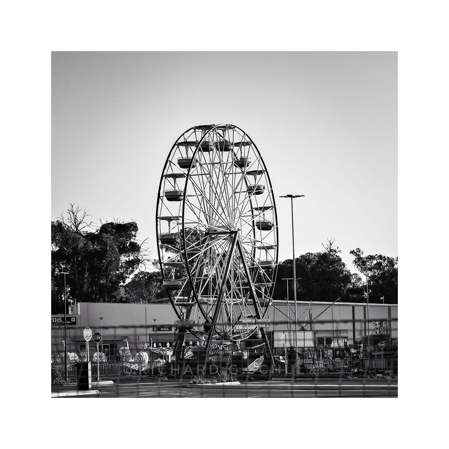 A ferris wheel at a circus. Image in black and white.