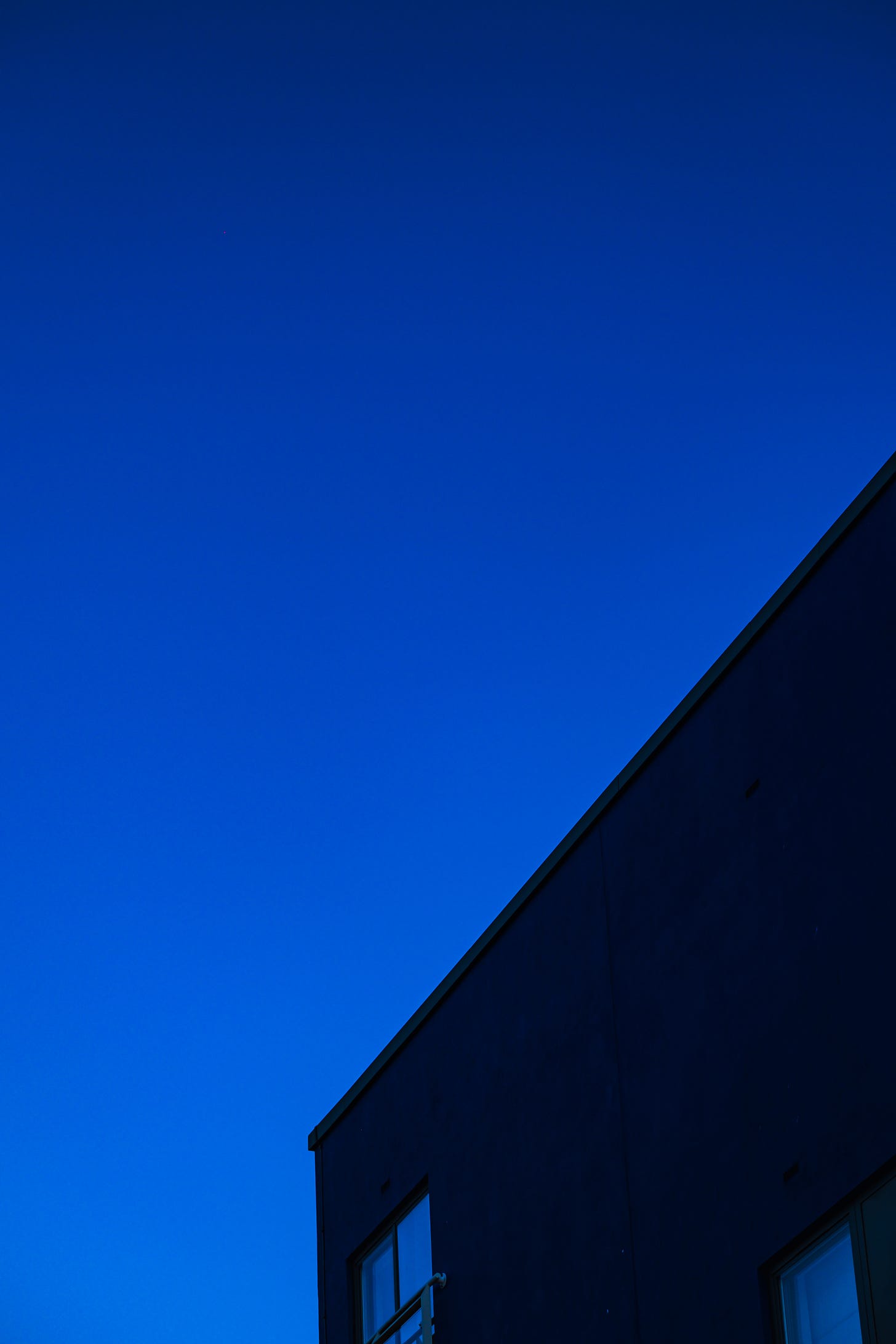 Sharp lines of concrete building against brilliant blue sky 