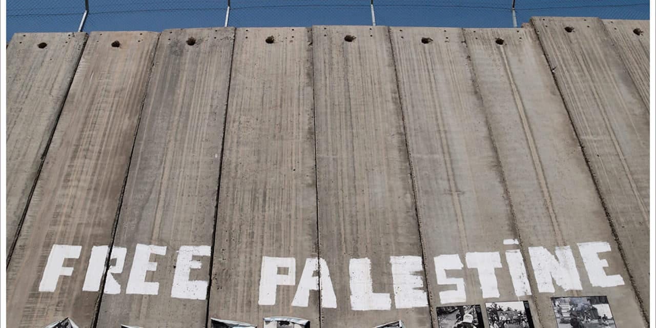 an image of the concrete separation wall with graffiti that reads "Free Palestine" an image of the concrete separation wall with graffiti that reads "Free Palestine"