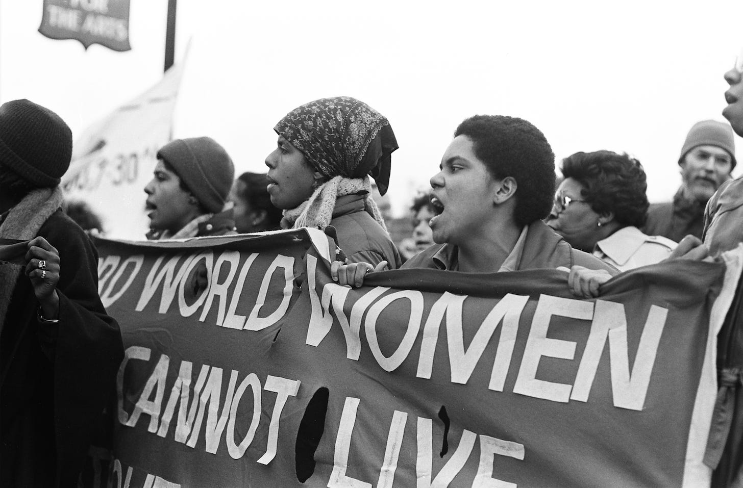 Black and white image of black women holding a banner with obstructed text reading "world women cannot live"
