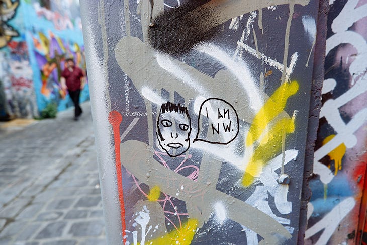 A Texta drawing on a grafitti wall of a head that looks like me. He's saying I AM NW.