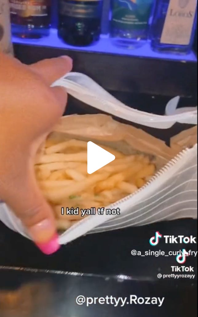 A still from the formally exquisite french fry purse TikTok, of a bartender’s hot pink manicured fingers spreading open a white handbag that is completely full of french fries. Incredibly, the beginning of the clip explains how this came to be. The caption reads: “I kid yall tf not.” 