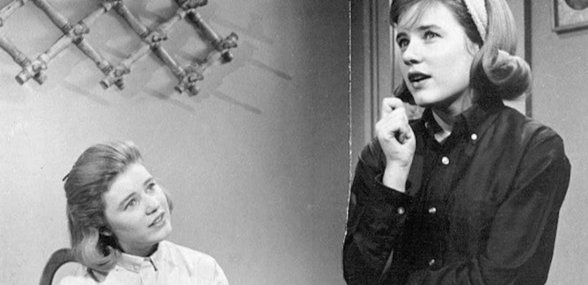 TV still from Patty Duke. A black-and-white still of twin sisters chatting.