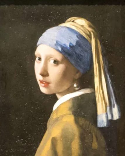 Vermeer painting Girl with a Pearl Earring, in which a girl looks over her left shoulder toward the viewer with a long veil trailing down her back and her head wrapped.