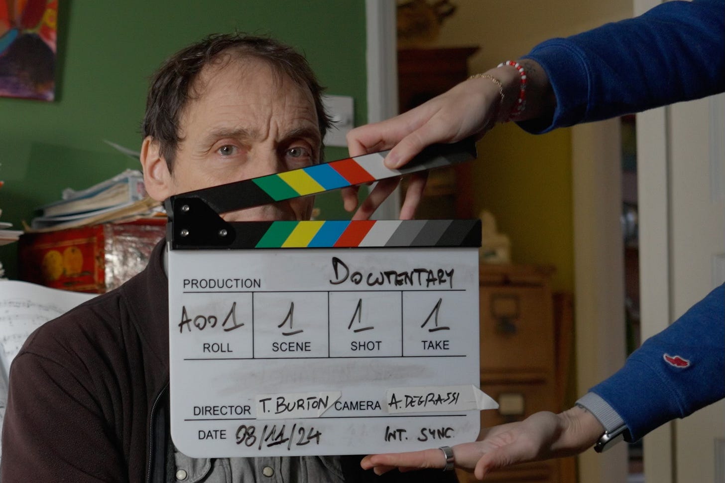 A man's face obscured by a clapperboard for a documentary