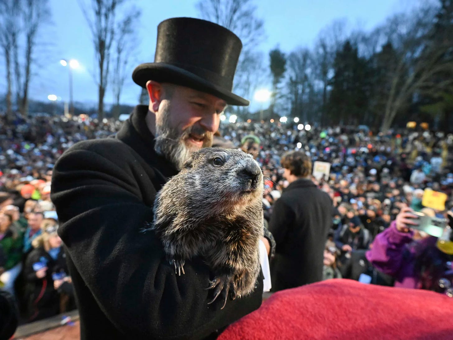 The groundhog being held by a man in a black coat and top hat
