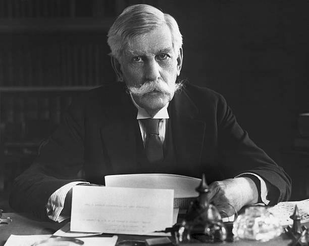 Oliver Wendell Holmes , Associate Justice of the Supreme Court, is shown seated at his desk. Photograph.
