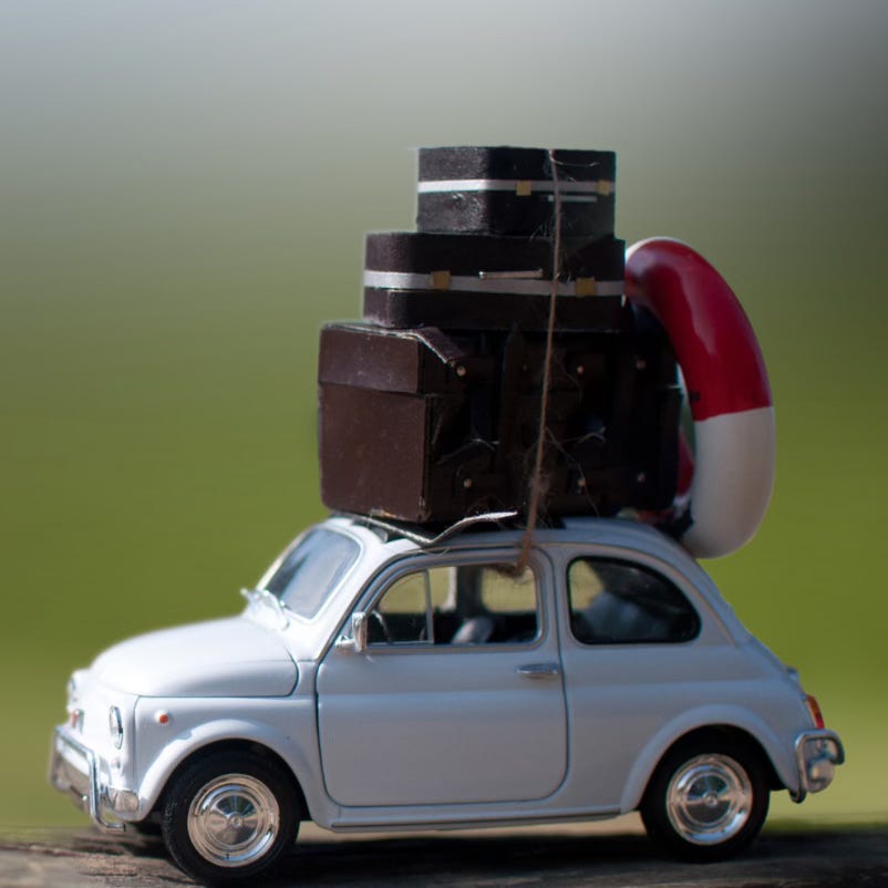 Silver toy car, laden with baggage and a small life preserver tied to the roof
