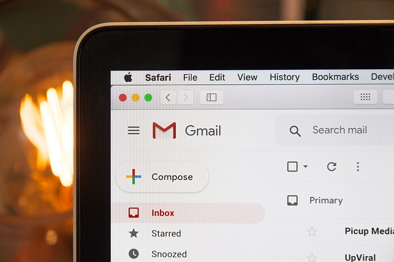 zoomed in photo of laptop with Gmail open, with blurry light bulb in the background