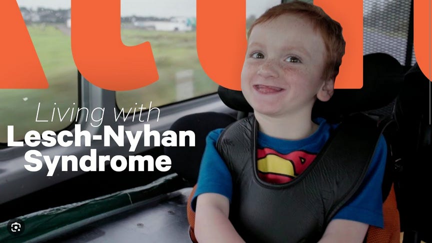A smiling five-year-old boy with red hair and no teeth sitting in a car, in a disability-adapted booster seat; text reads "Living with Lesch-Nyhan syndrome"