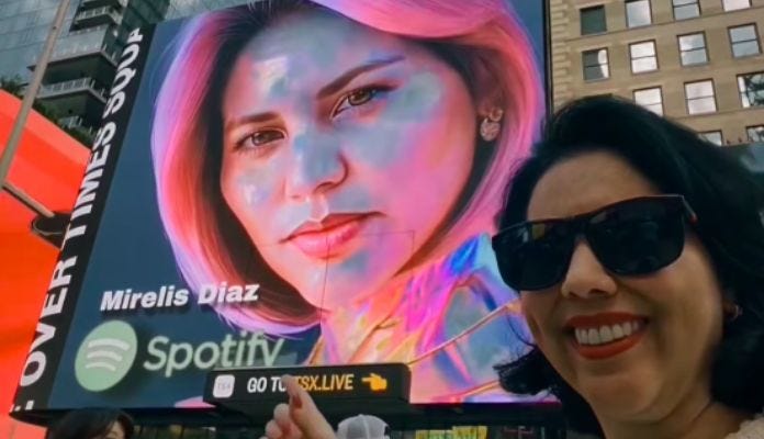 Imagem da matéria: Esposa do Faraó do Bitcoin aparece em telão da Times Square fazendo propaganda de músicas dela