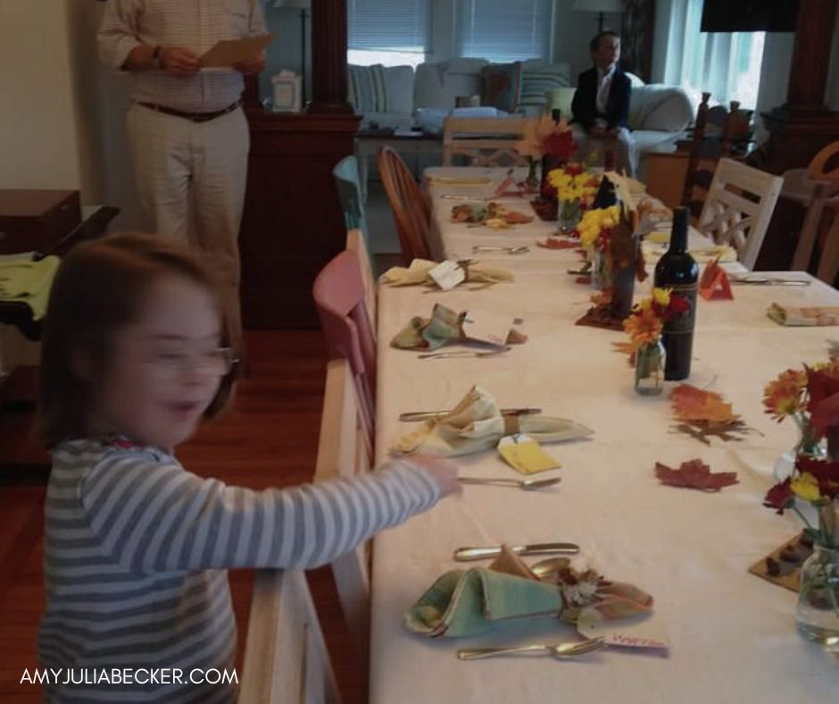  A Thanksgiving table set with napkins, cutlery, and fall decorations. Penny, in a striped shirt, is reaching toward the table.