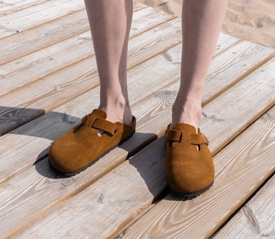 a person standing on a wooden dock wearing brown shoes a person standing on a wooden dock wearing brown shoes