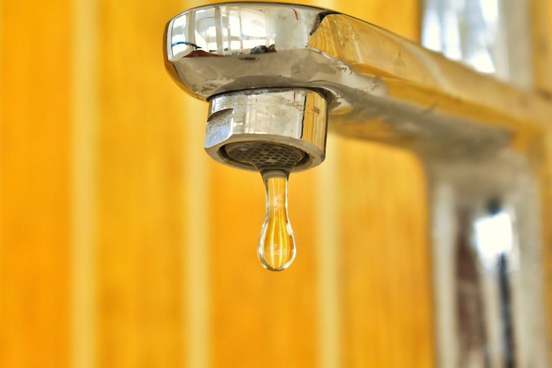 Free A close-up shot of a water droplet hanging from a stainless steel faucet, highlighting surface tension. Stock Photo Free A close-up shot of a water droplet hanging from a stainless steel faucet, highlighting surface tension. Stock Photo