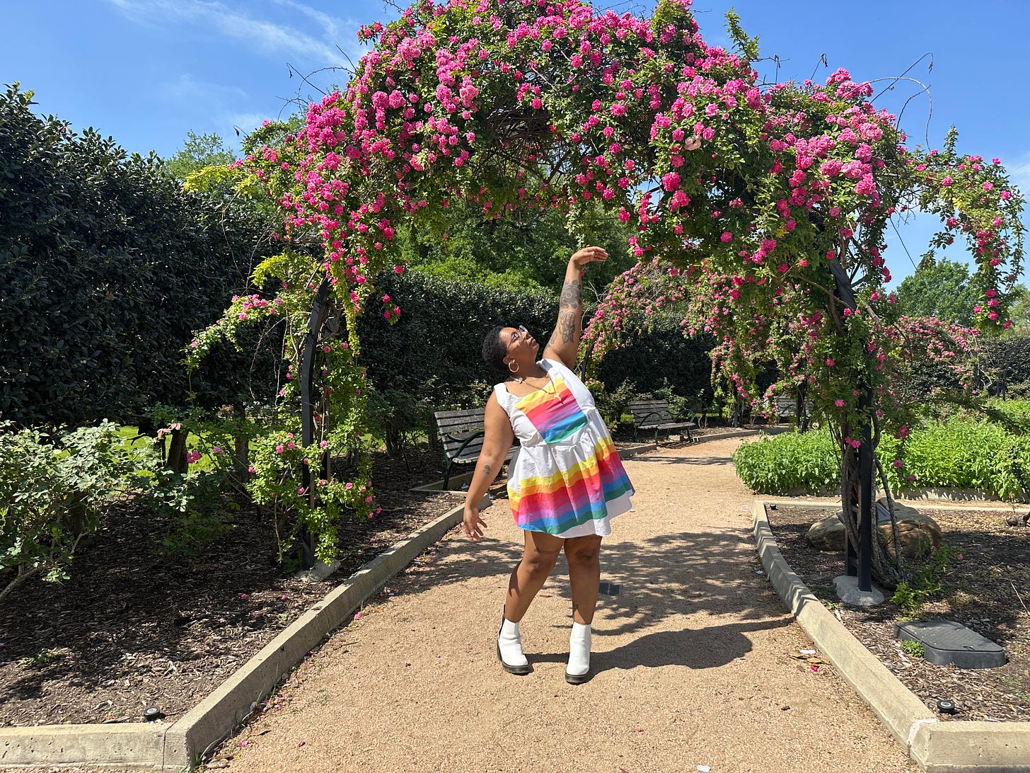 danielle standing in a garden wearing a rainbow dress she made and white high heel boots